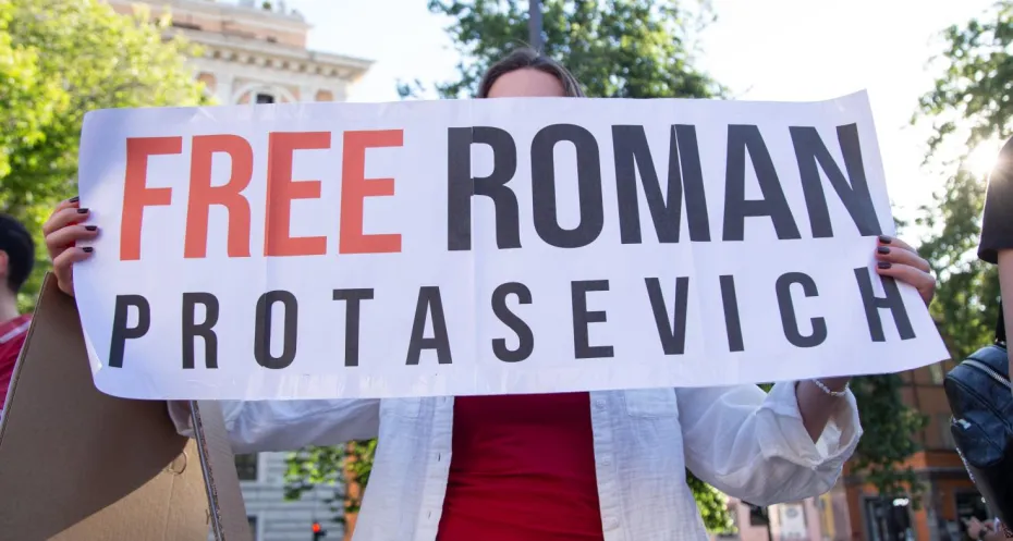 Een banner met de tekst Free Roman Protasevich. Het wordt vastgehouden door een vrouw tijdens een demonstratie