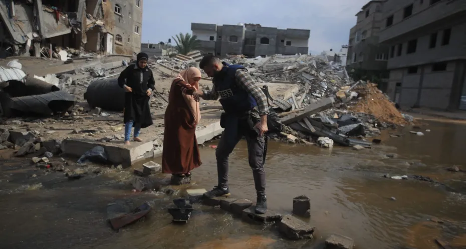 Journalist helps Palestinian woman amidst bombed buildings in Gaza